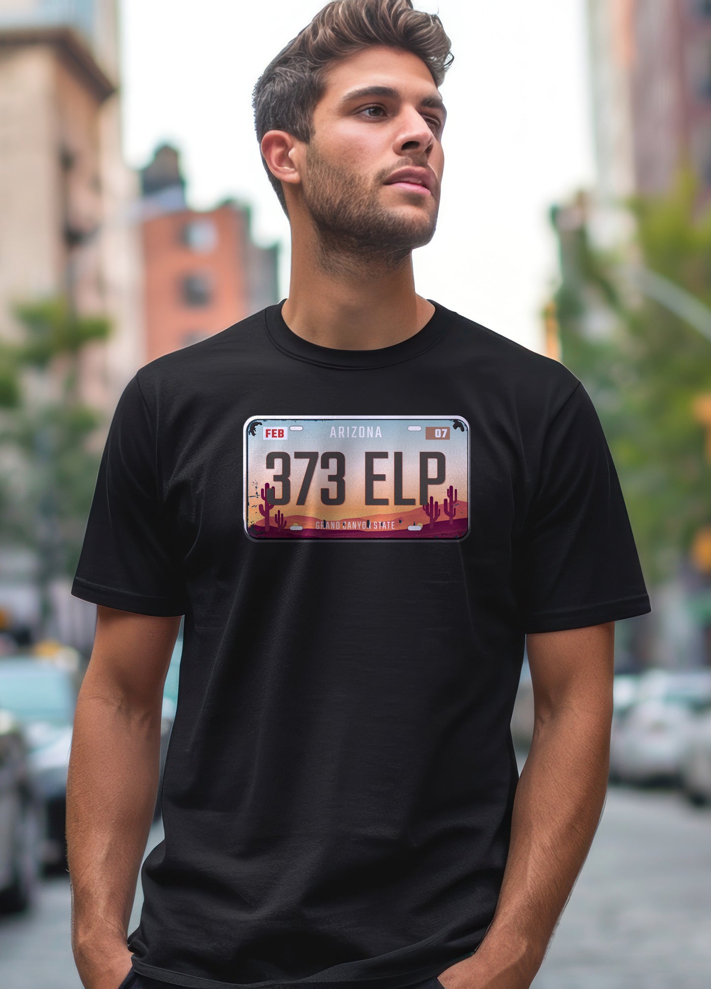 Man wearing a black t-shirt with an Arizona license plate design in an urban setting