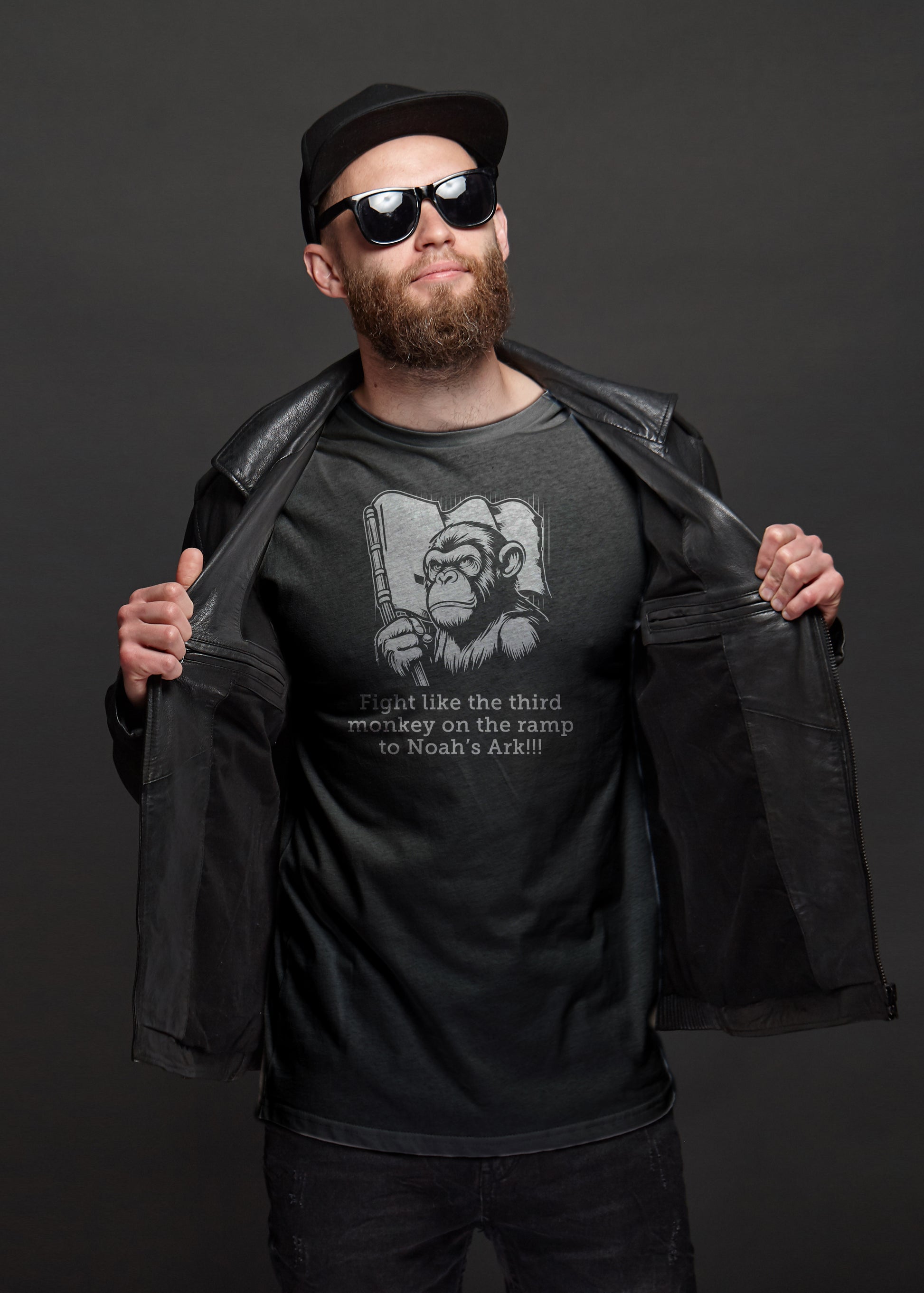 Man wearing a black t-shirt with a angry monkey graphic design and text, holding a black leather jacket open against a dark background.