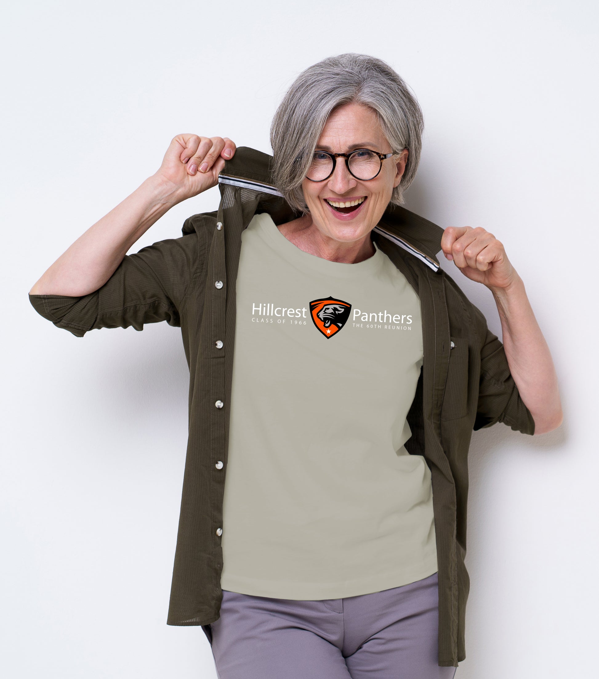 Person wearing a sand t-shirt with a Hillcrest emblem and text, standing against a white background