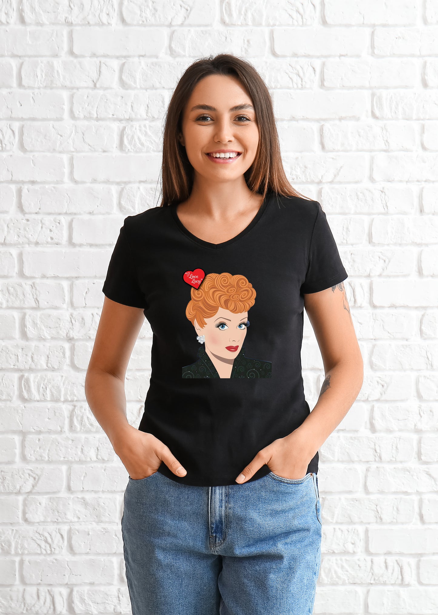 Woman wearing a black t-shirt with a graphic design of Lucille Ball's face with a red heart on a white brick wall background.