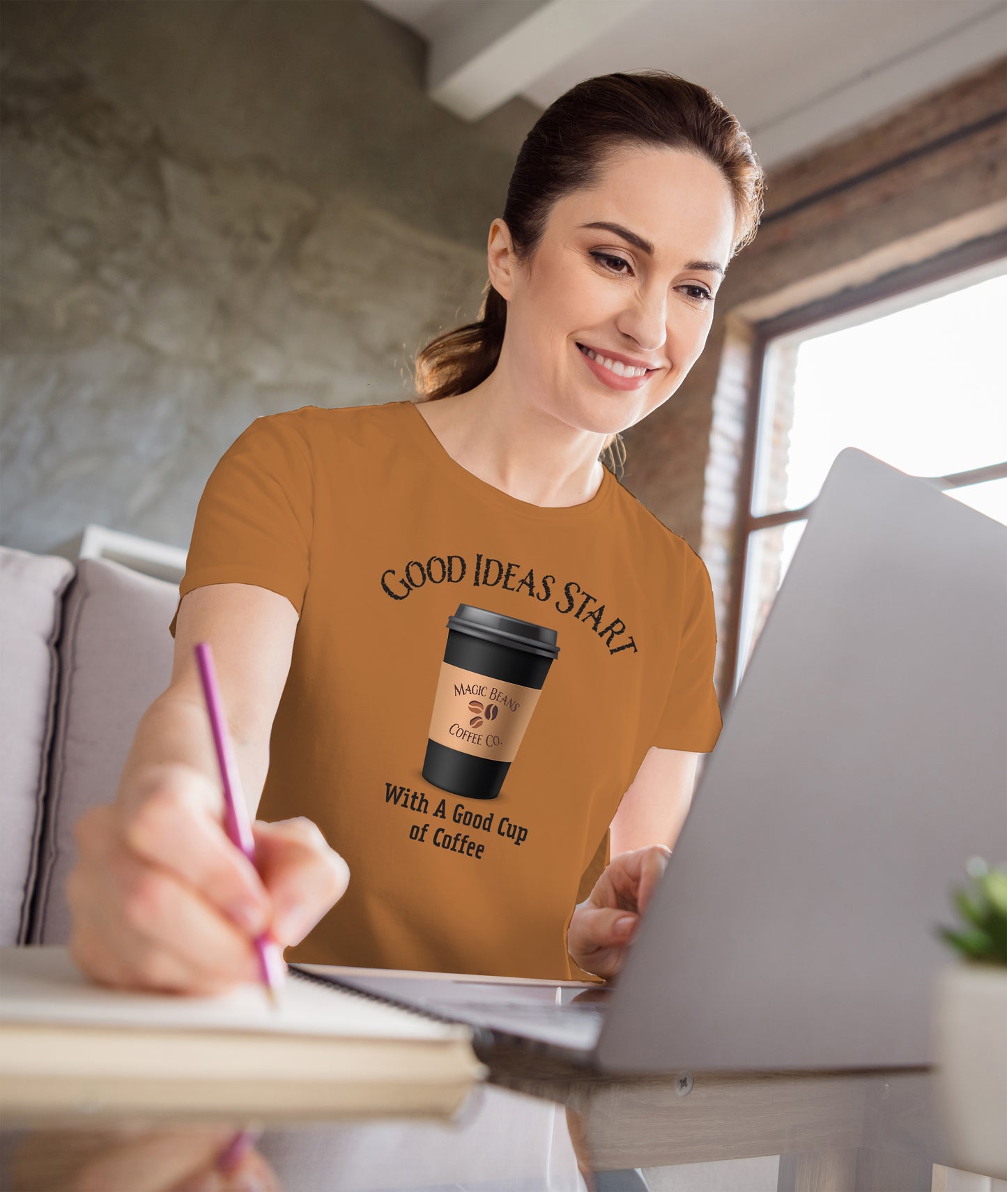 Woman wearing a t-shirt with a coffee cup graphic and text, sitting at a desk.