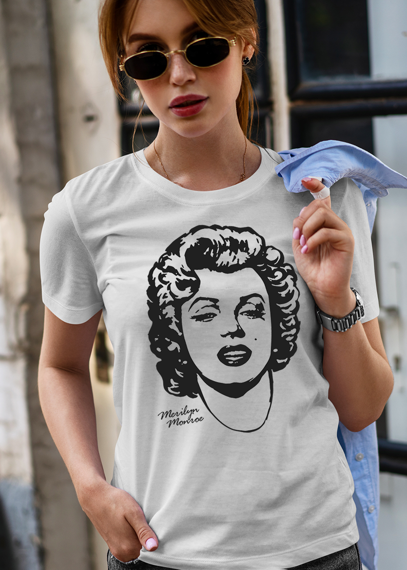 Person wearing a white t-shirt with an image of Marilyn Monroe, standing against an urban background.
