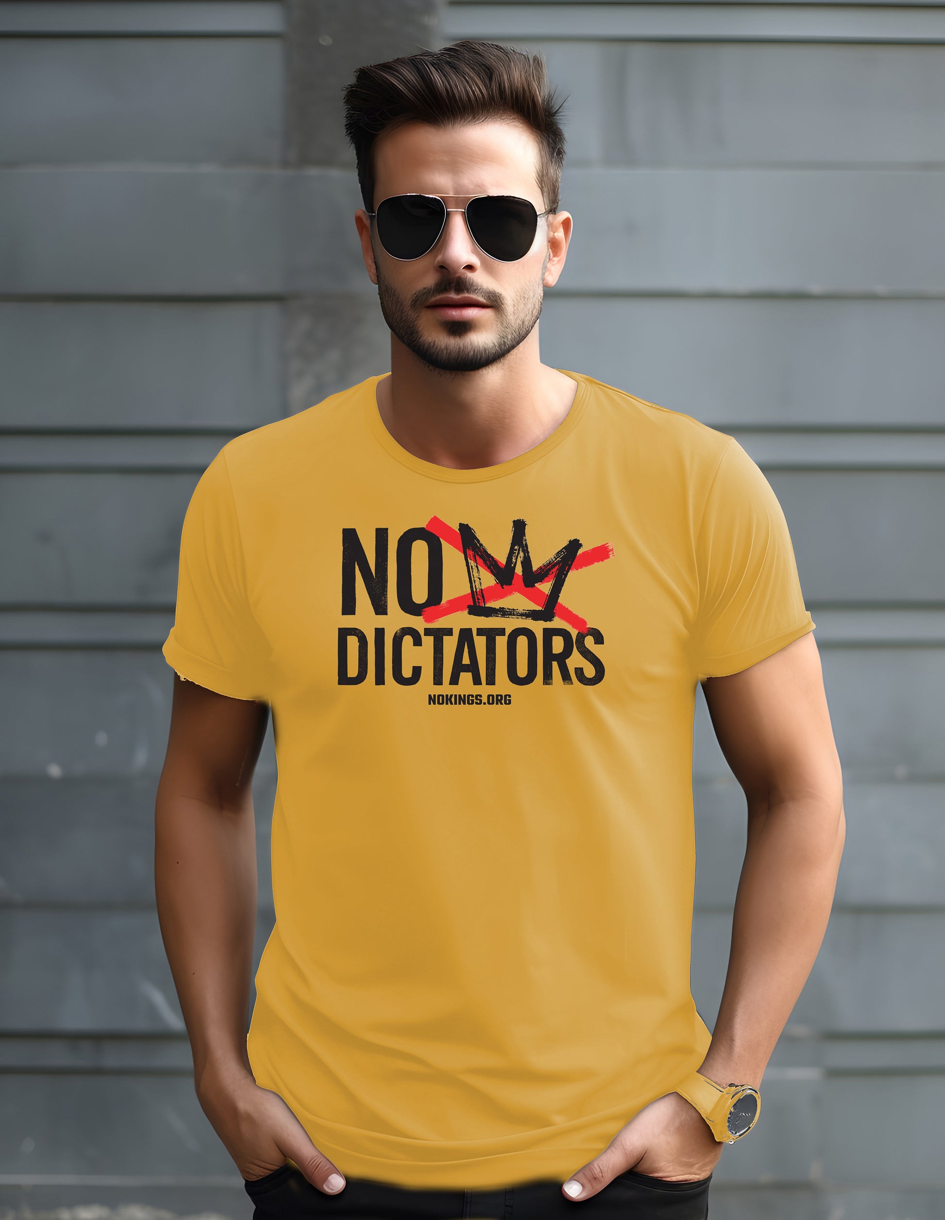 Man wearing a yellow t-shirt with 'No 
 Dictators' text against a gray wall.
