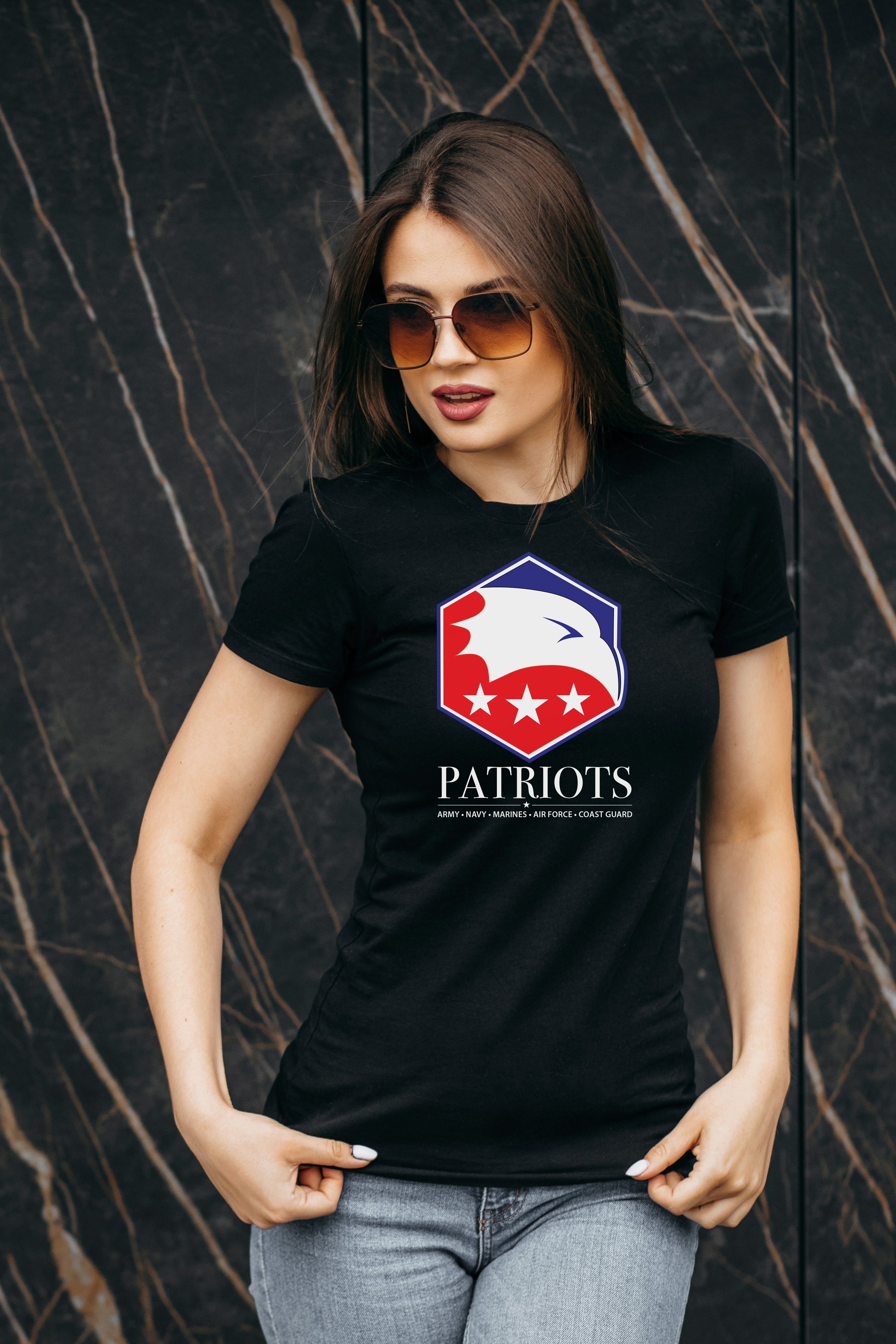 Woman wearing a black t-shirt with a 'Patriots' logo against a dark textured background