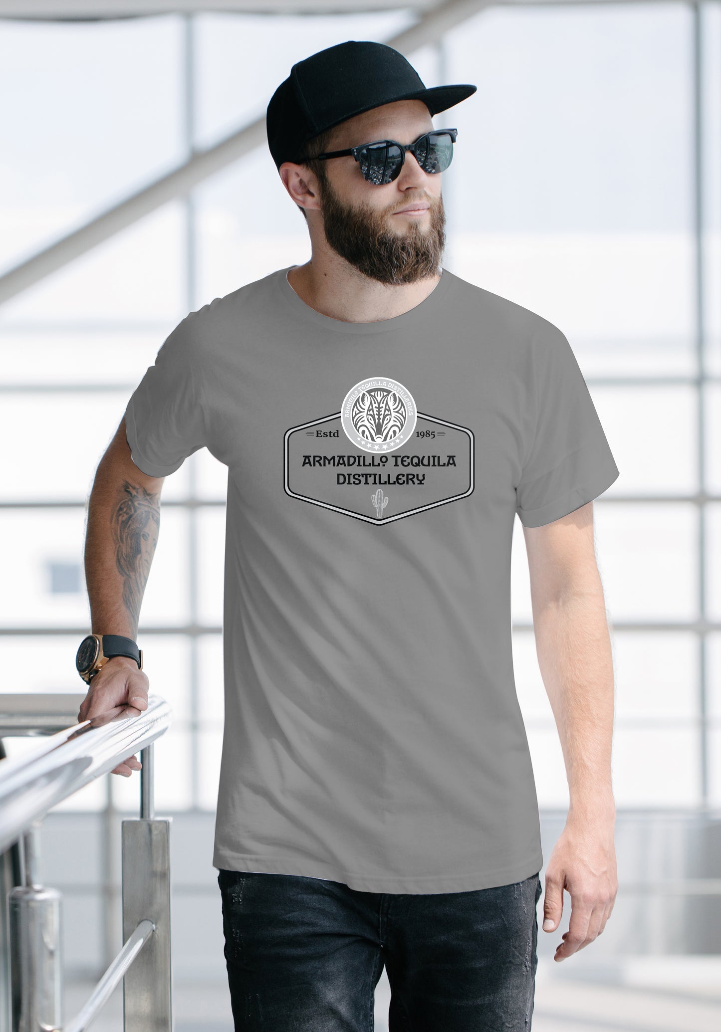 Man wearing a gray t-shirt with a Tequila Distillery logo and text, standing indoors.