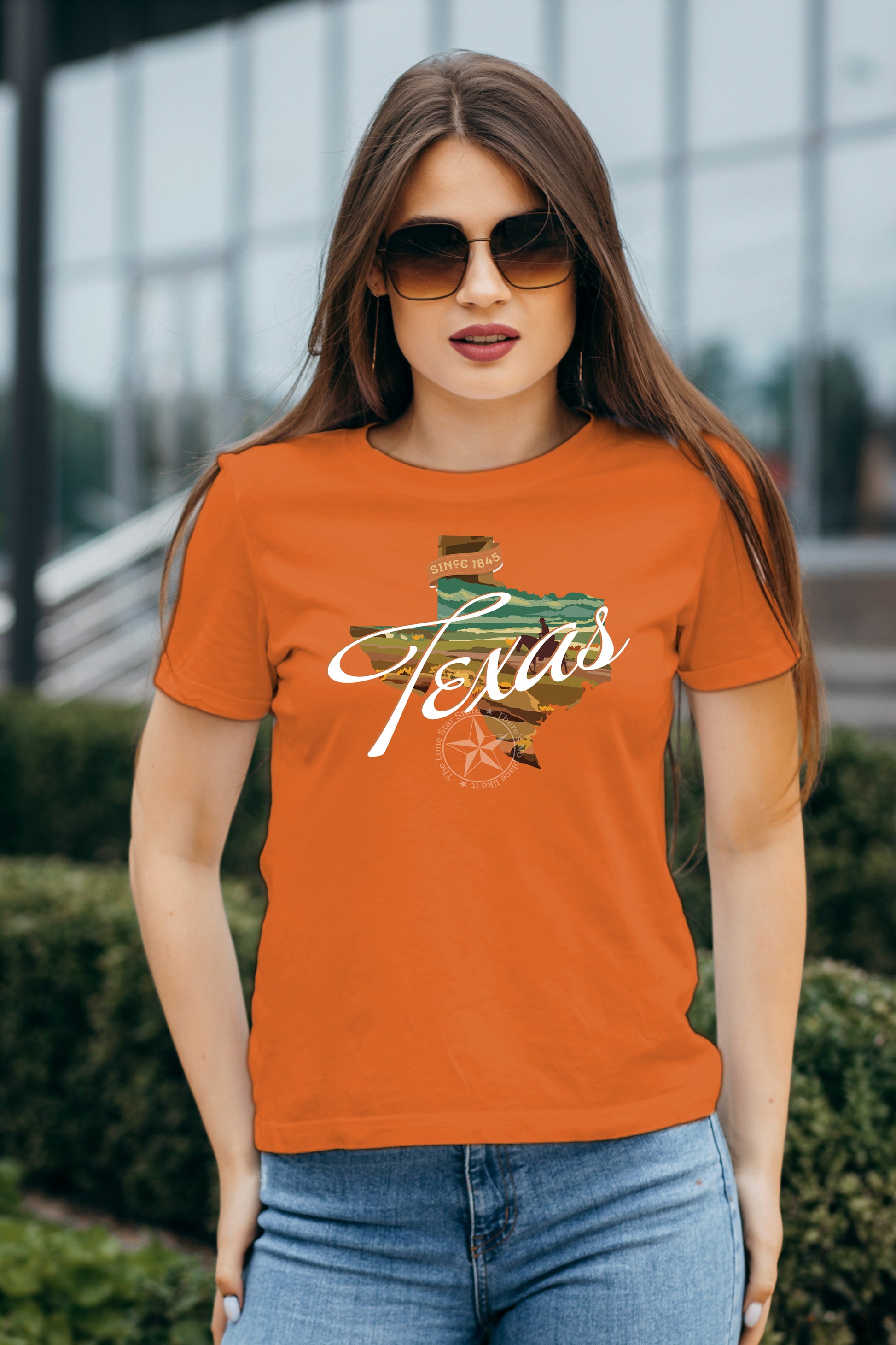 Woman wearing an orange 'Texas' t-shirt with a map design outdoors.