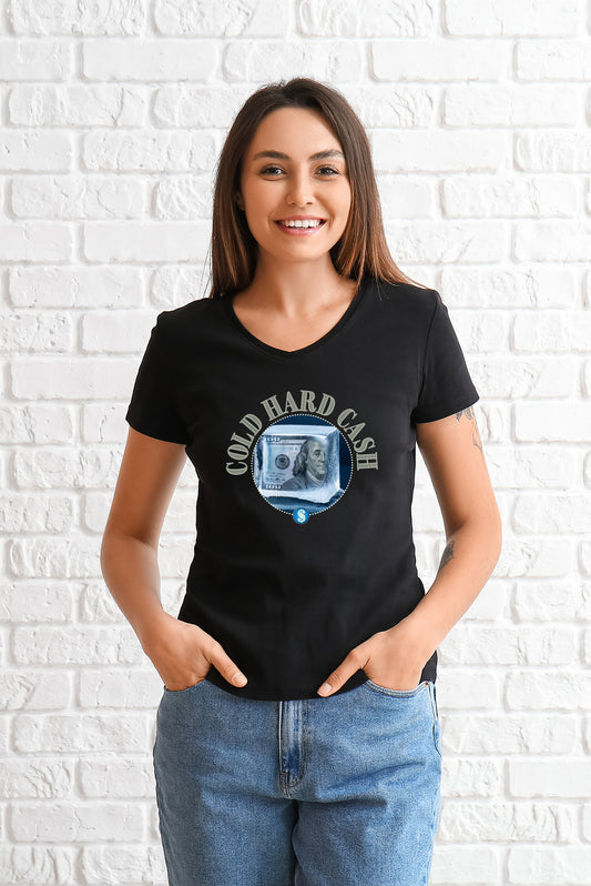 Woman wearing a black t-shirt with a Cold Cash graphic design against a white brick wall.