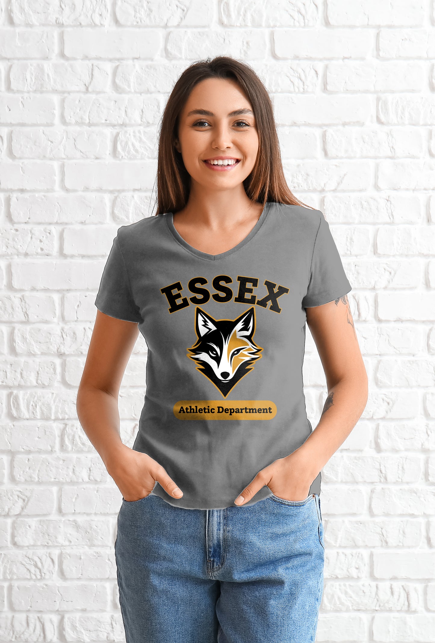 Woman wearing a gray t-shirt with 'Essex Athletic Department' logo against a white brick wall.
