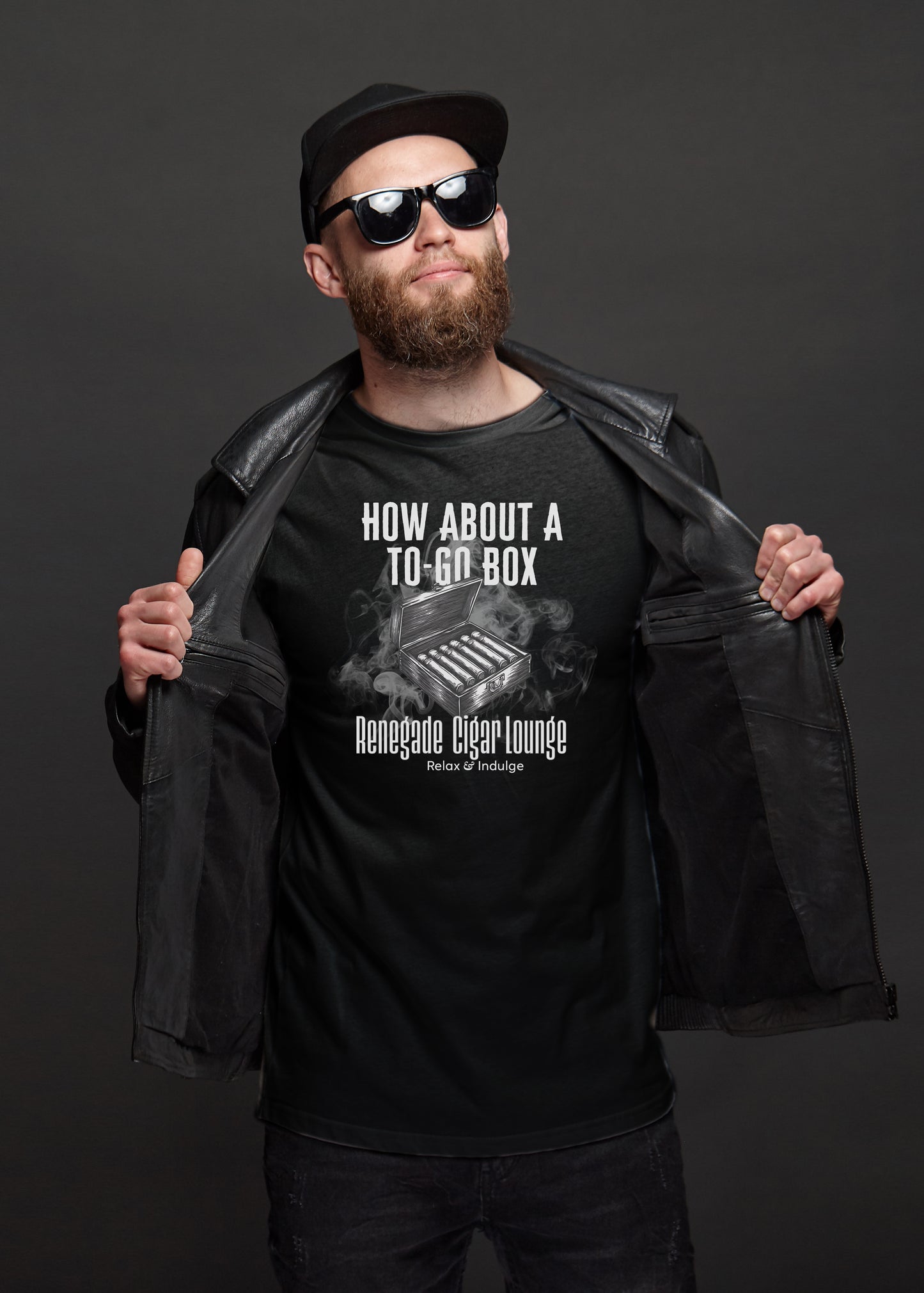 Man wearing a black t-shirt with text and cigar box graphics, holding a black jacket against a dark background